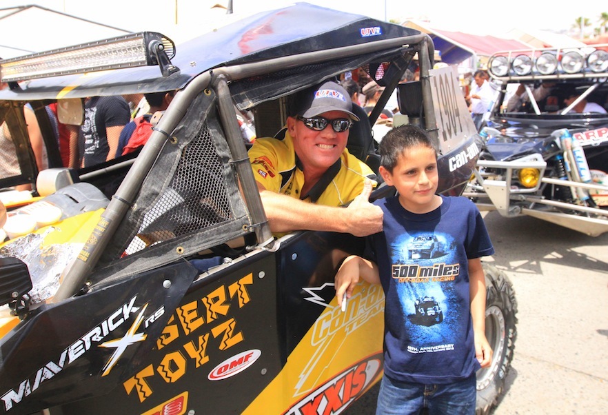 Cory Sappington and his No. 1904 Desert Toyz/ Can-Am Maverick 1000R X rs pose with a young fan at the starting line of the 40th annual Baja 500 in Mexico.